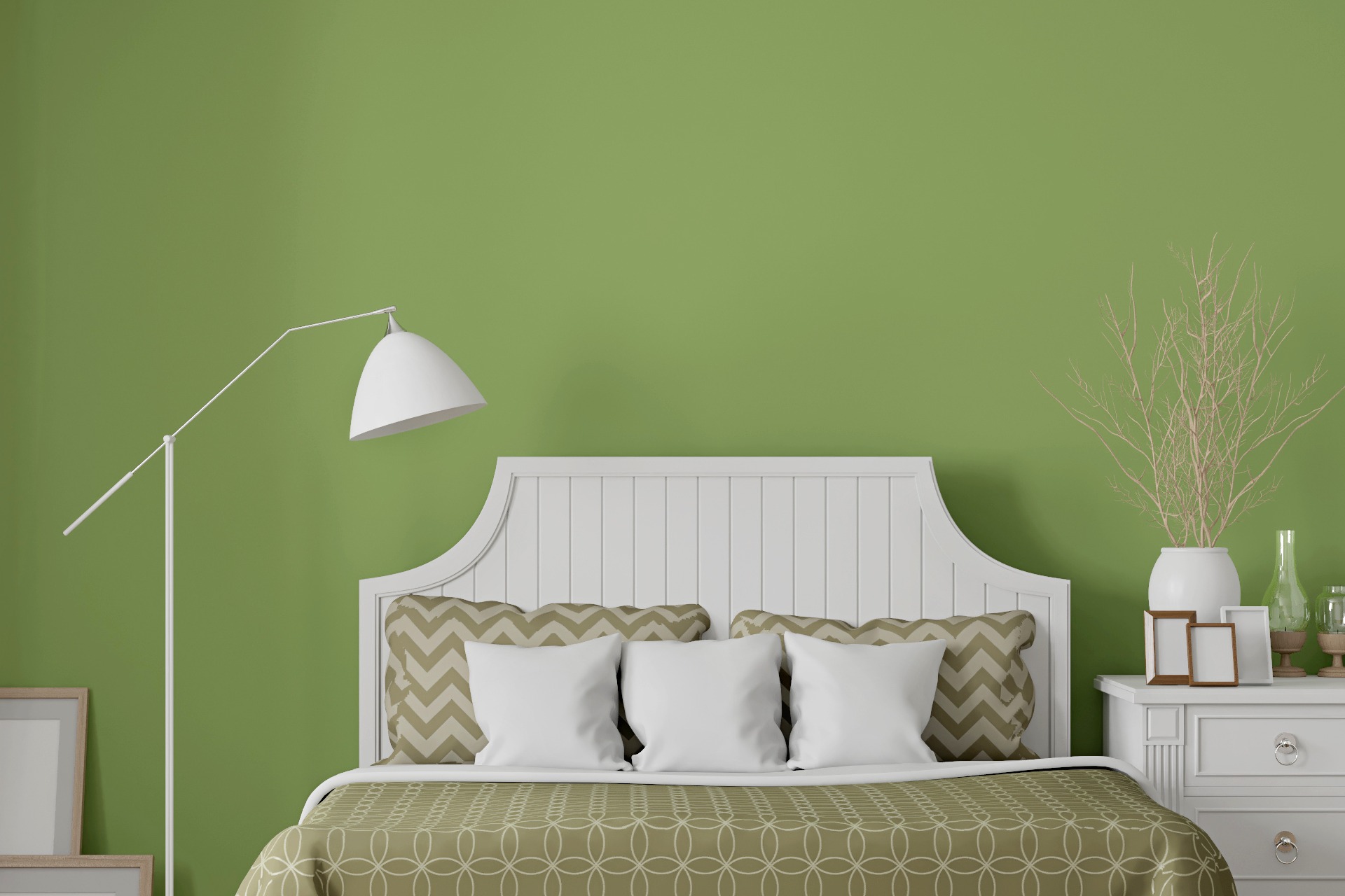 Lámpara al lado de una cama con cabecero blanco sobre una pared verde claro